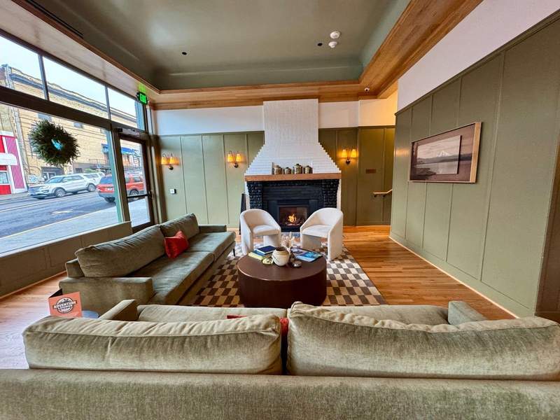 Plush green velvet couches nestle next to the hotels original brick fireplace painted white with a black insert and hardwood mantle.