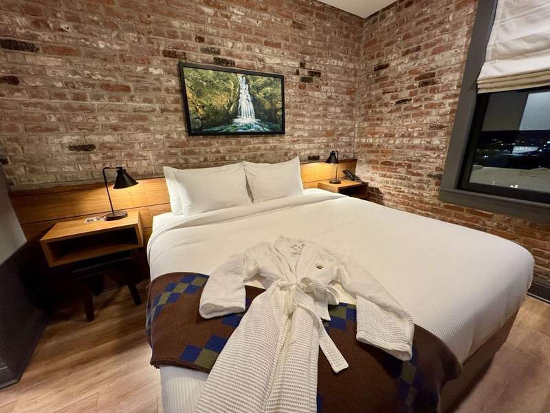 Original brick walls waterfall painting and king size bed with white sheets and draped with a spa robe.