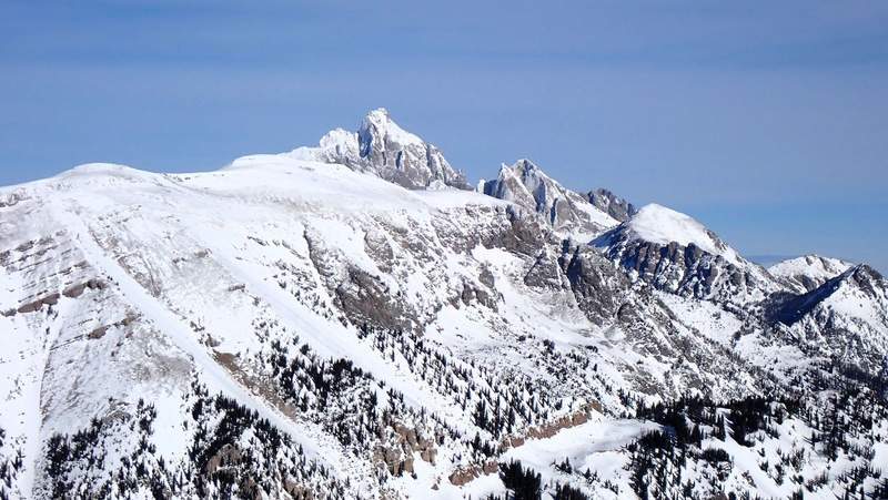 Grand Teton National Park in the wintertime showcases snow capped jagged mountain caps against a vibrant blue sky.