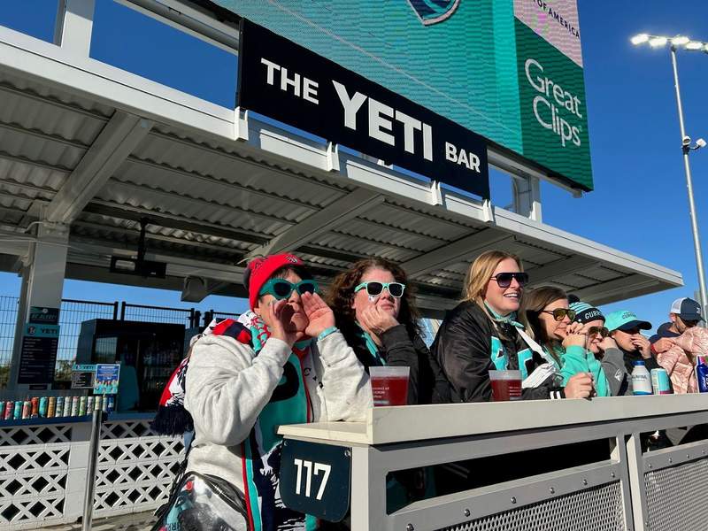 Six women cheering on the Current players in front of The Yeti Bar.