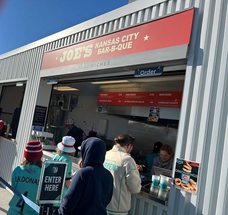 People waiting in line at a barbecue stand called Joes Kansas City