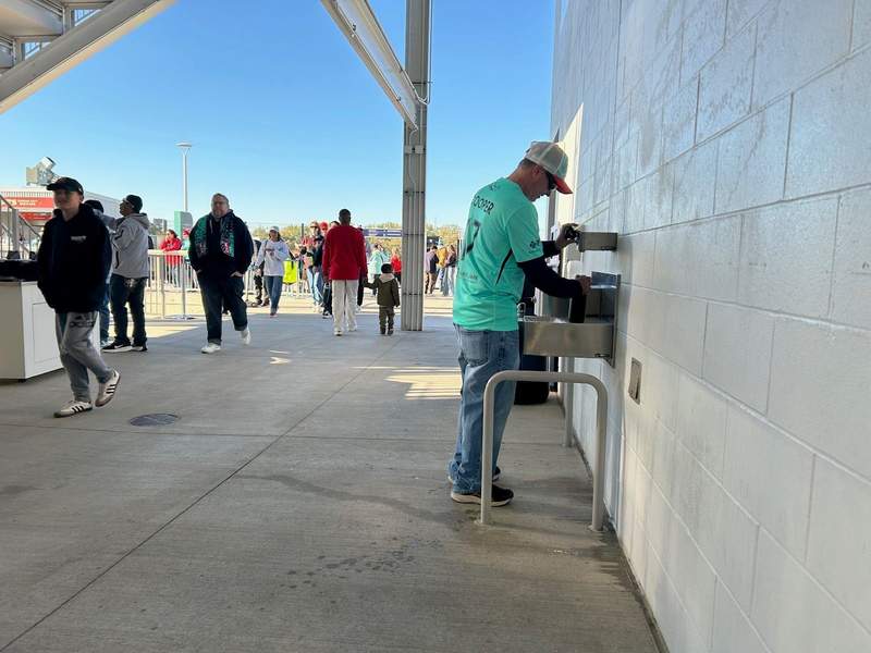 A man filling an bottle of water which is allowed to be brought into the Stadium.