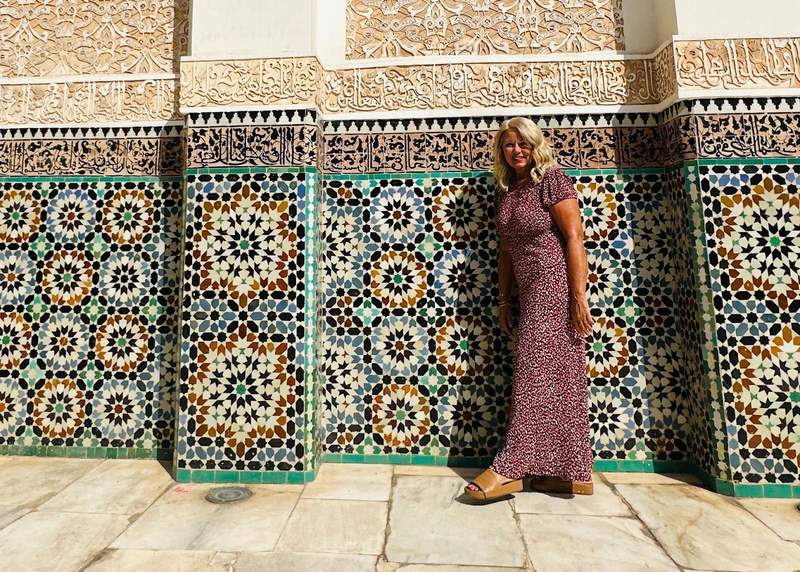 A woman looking at detailed tile work in the courtyard of a Moroccan riad