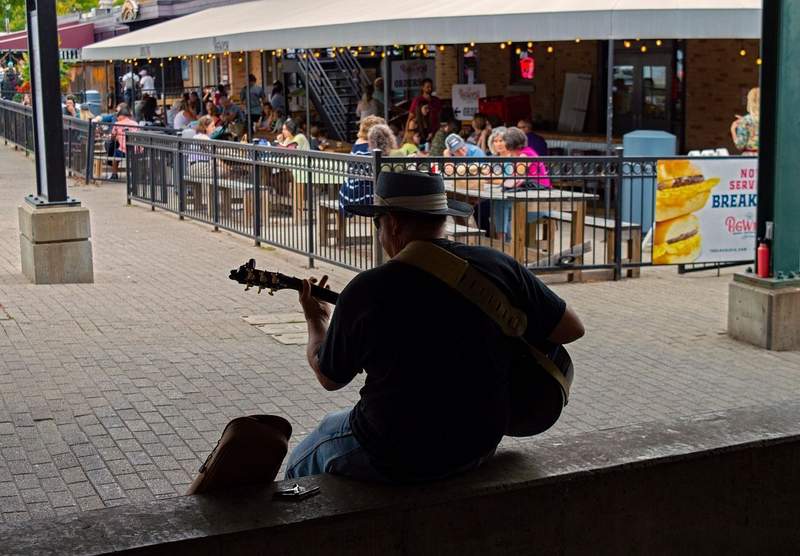 Musician playing at the Kansas City Market while diners enjoy midday meal.