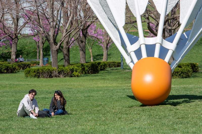 A man and a woman enjoy a day of sun sitting outside one of the Art Museums giant shuttlecocks.
