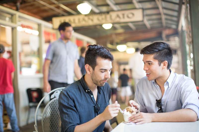 Two men share a sweet treat on one of the patios at the City Market.