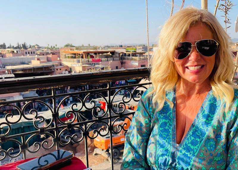 A woman eating at a rooftop restaurant in the Marrakech medina at sunset