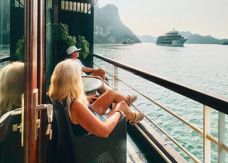 A couple sitting on a private balcony watching Ha Long Bay during a cruise