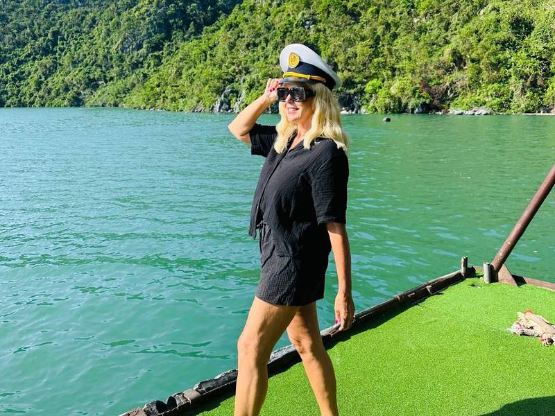 A woman wearing a captain hat on the deck of a boat in Ha Long Bay Vietnam