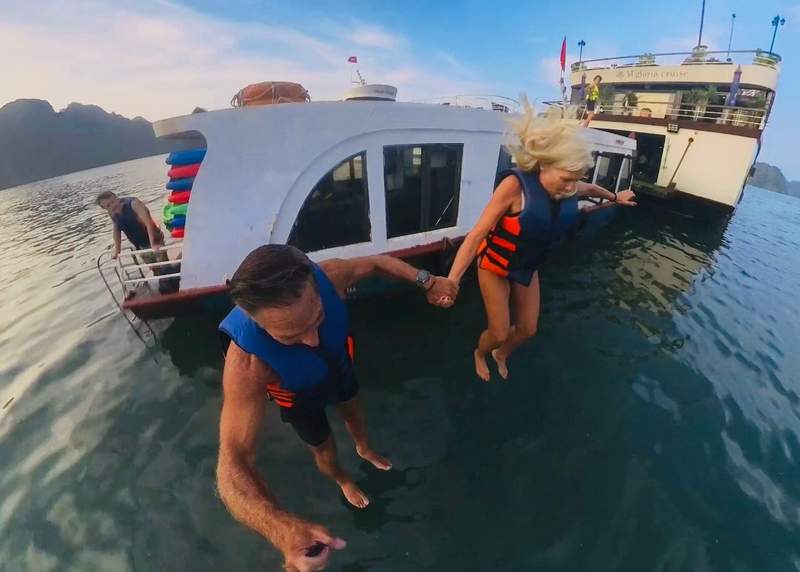 A couple jumping off the top of a boat into the water in Ha Long Bay Vietnam