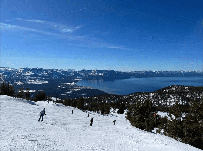People skiing on an easy slope looking over Lake Tahoe
