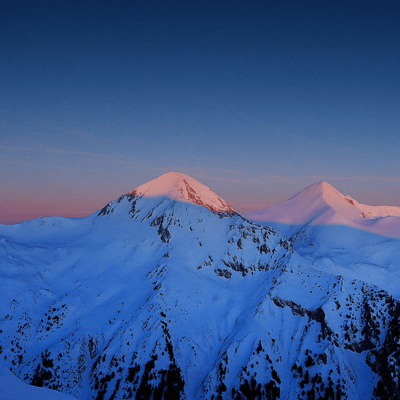 Setting sun on snow topped mountains