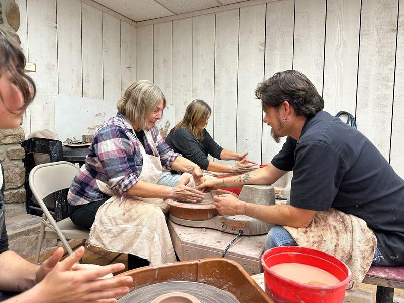 Several people working with clay in the pottery shop.