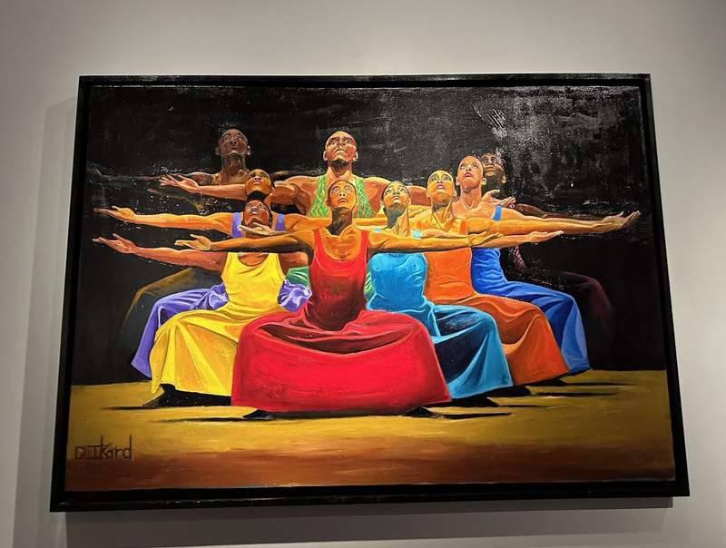 A colorful photo of nine people in bright colored clothing. 