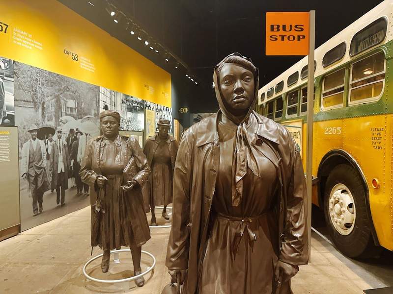 Statues of several African Americans beside a bus stop. 