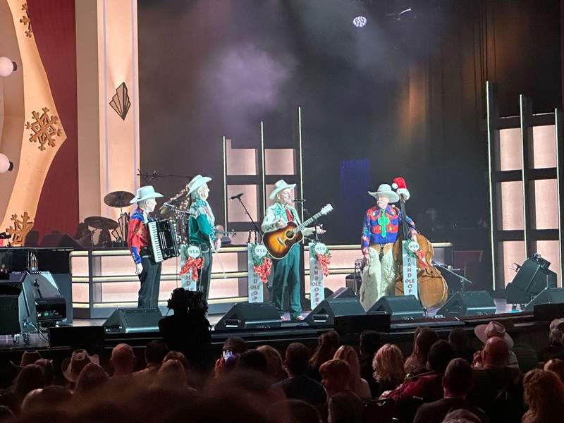 four men with instruments standing on a stage.