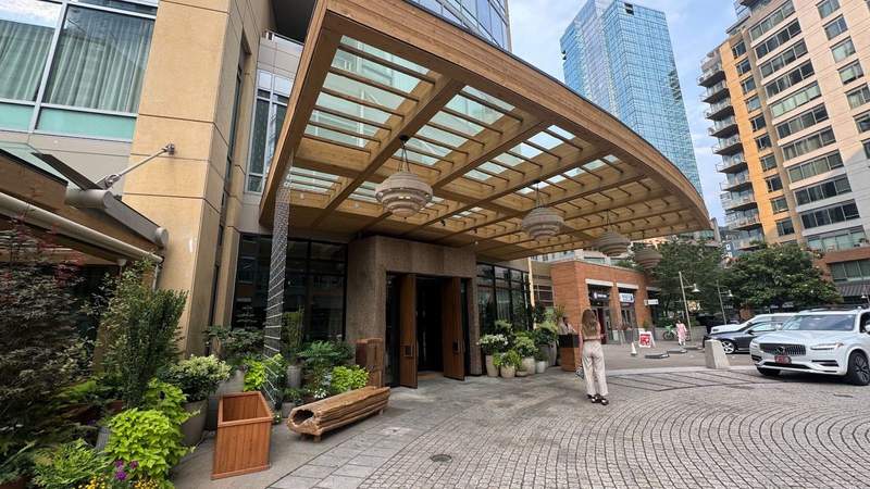 grey brick and wooden entryway with green plants outside of the 1 Hotel Seattle