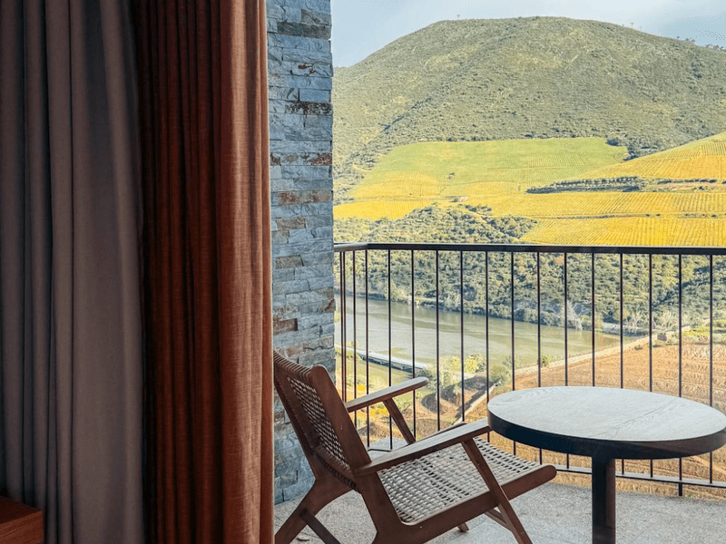A chair and table sit on a hotel room balcony overlooking the Douro at Quinta Sao Jose do Barrilario.
