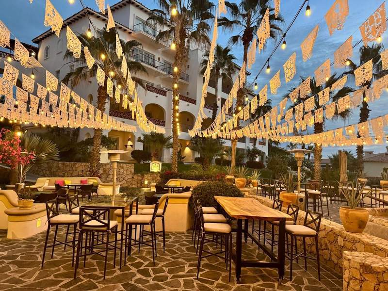 White Mexican papel picado hang above tables and chairs at dusk at Hacienda del Mar Los Cabos