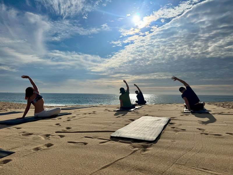 Four people do yoga on the beach