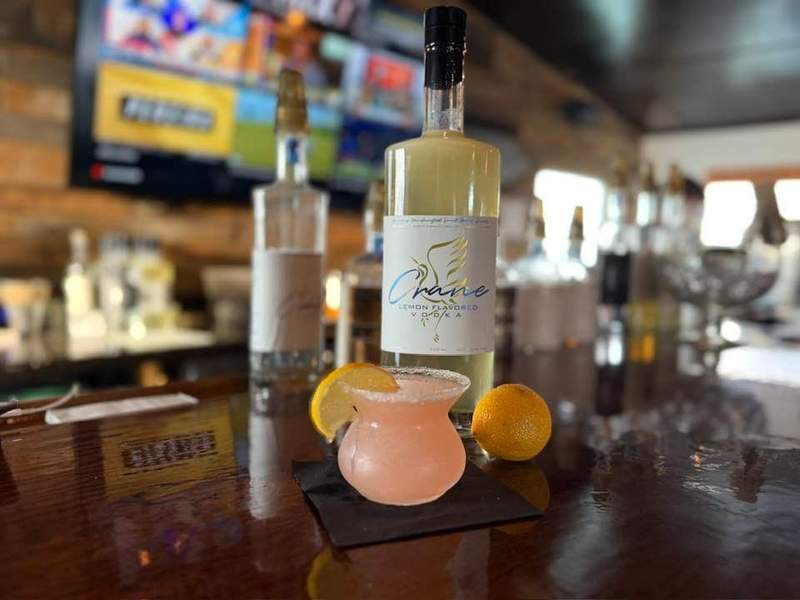 Pink cocktail with an orange slice sitting on a bar