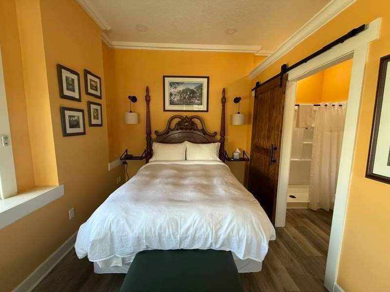 Antique bed in a room with gold walls and artwork.