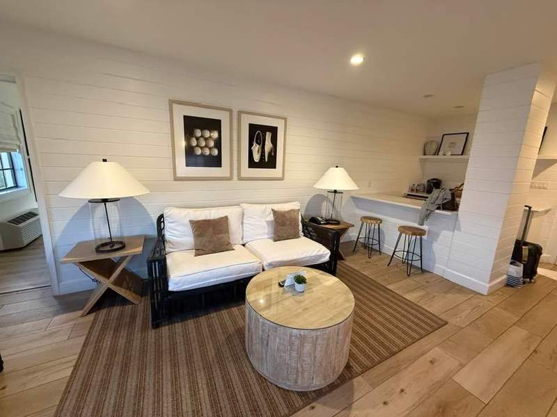 Living room at Inn on the Lakes with white loveseat brown rug and white subway brick walls