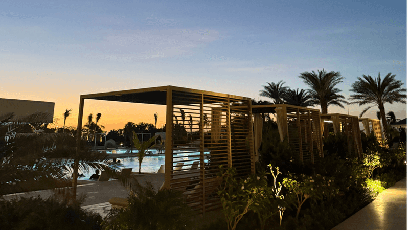 late evening view of pool with daybeds and palm trees