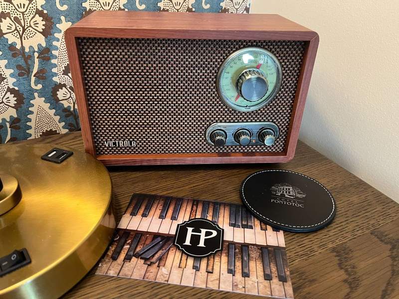 An old fashioned Victrola radio sits on the table with a Hotel Pontotoc post card. 