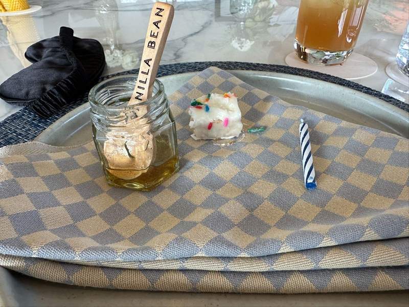 Honey a piece of cake and an candle sitting on a napkin on a plate.