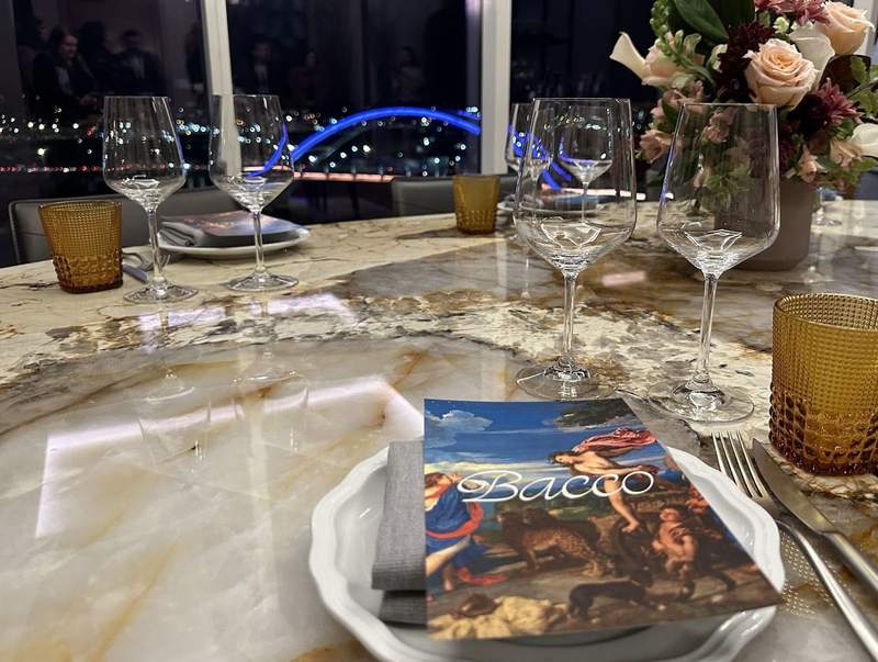 A table set for dinner near a window overlooking a bridge. 