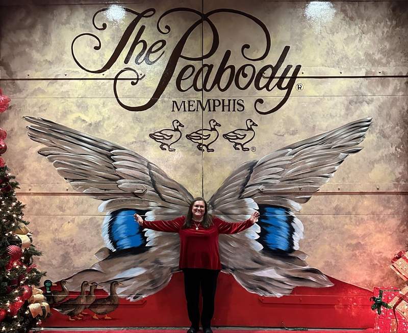 A lady in front of a wing mural.