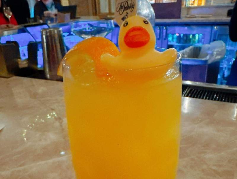 A yellow drink with a yellow rubber ducky sitting on the top.