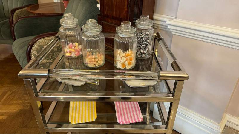Glass jars filled with sweets along with yellow and pink treat bags in the lobby of The Stafford London. 