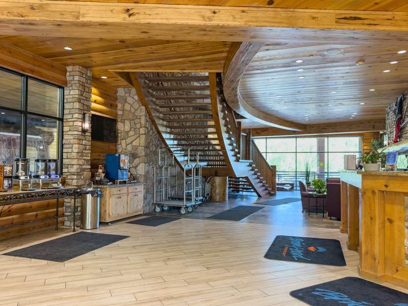 Hotel lobby with coffee thermos containers luggage carts a staircase and a view of the outside.