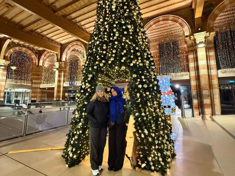 Kim and daughter in front of Christmas tree surrounded by lights in Amsterdam Centraal Station.