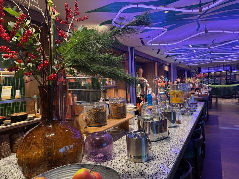 Breakfast buffet presentation with lots of fresh fruit waters and vases full of colorful plants.