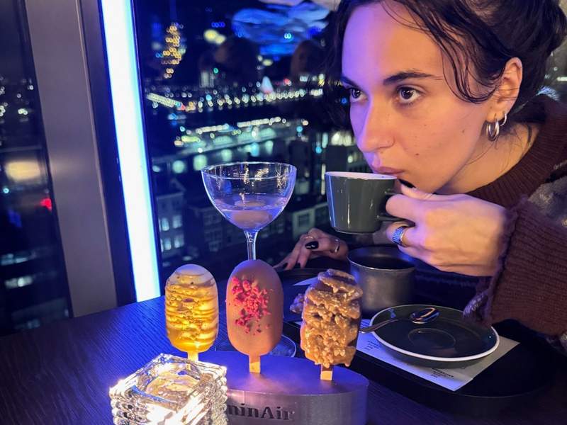 Woman sipping espresso and eating 3 mini magnum ice cream bars at DoubleTree Amsterdam Centraal Station rooftop bar LuminAir.