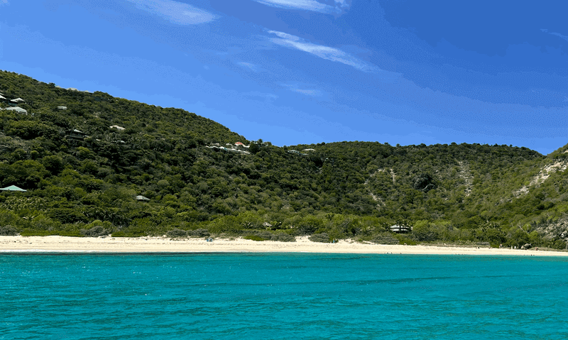 Crystal clear waters leading to quiet beach with soft sands and lush hilltops