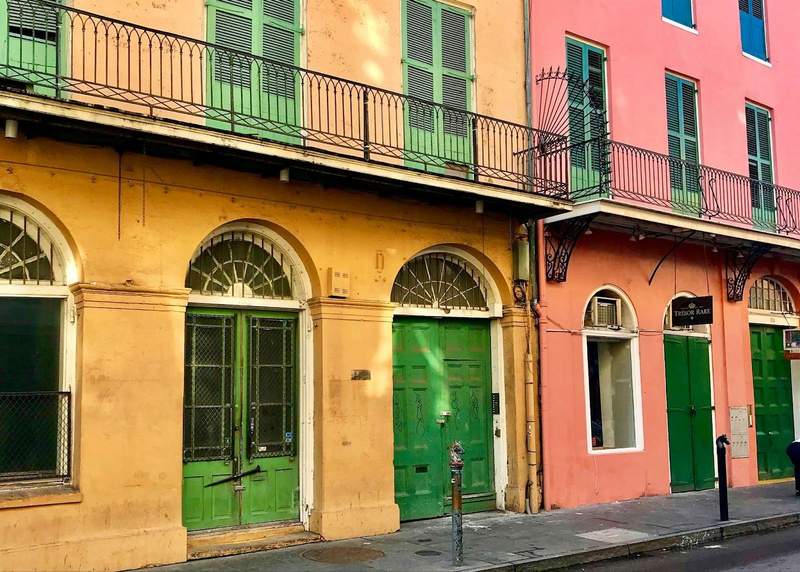 Pink and orange buildings with green doors and wrought iron balconies