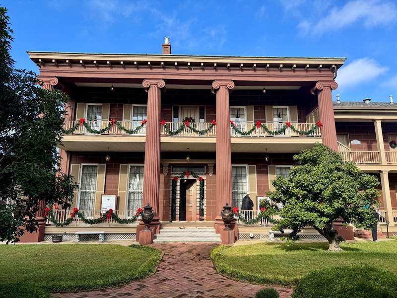 A majestic two story mansion with four dusty rose columns.