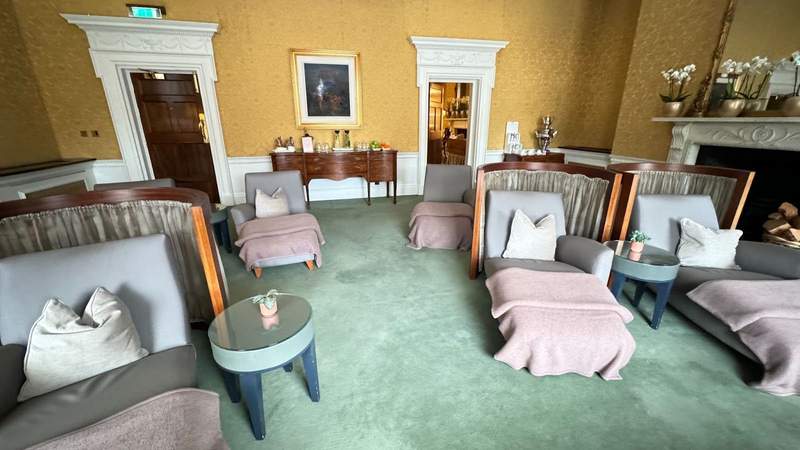 lounge chairs with pink blankets and mini green tables on top of green carpeting in a yellow room in the spa at The Shelbourne