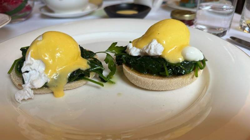 White plate with two english muffins with green spinach and a white poached egg with yellow hollandaise sauce from The Shelbourne. 