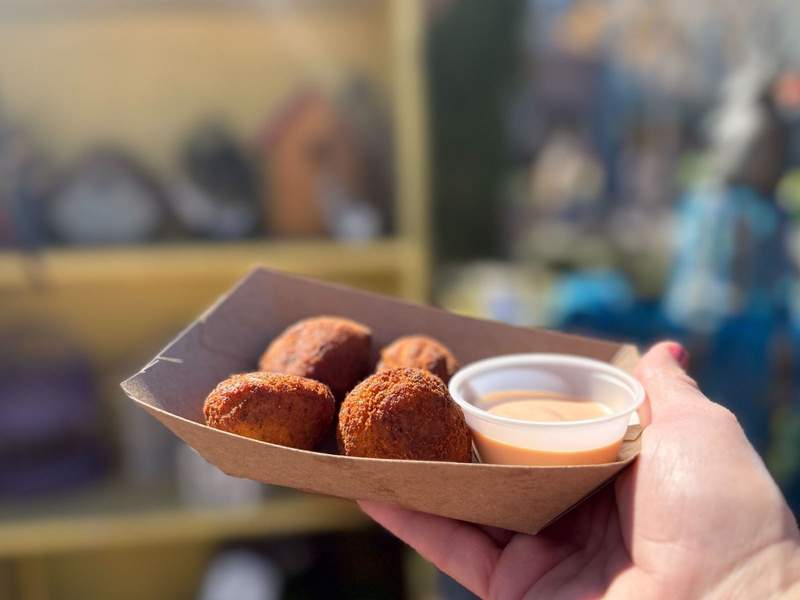 Person holding Pastelon Fritters at Universal Mardi Gras