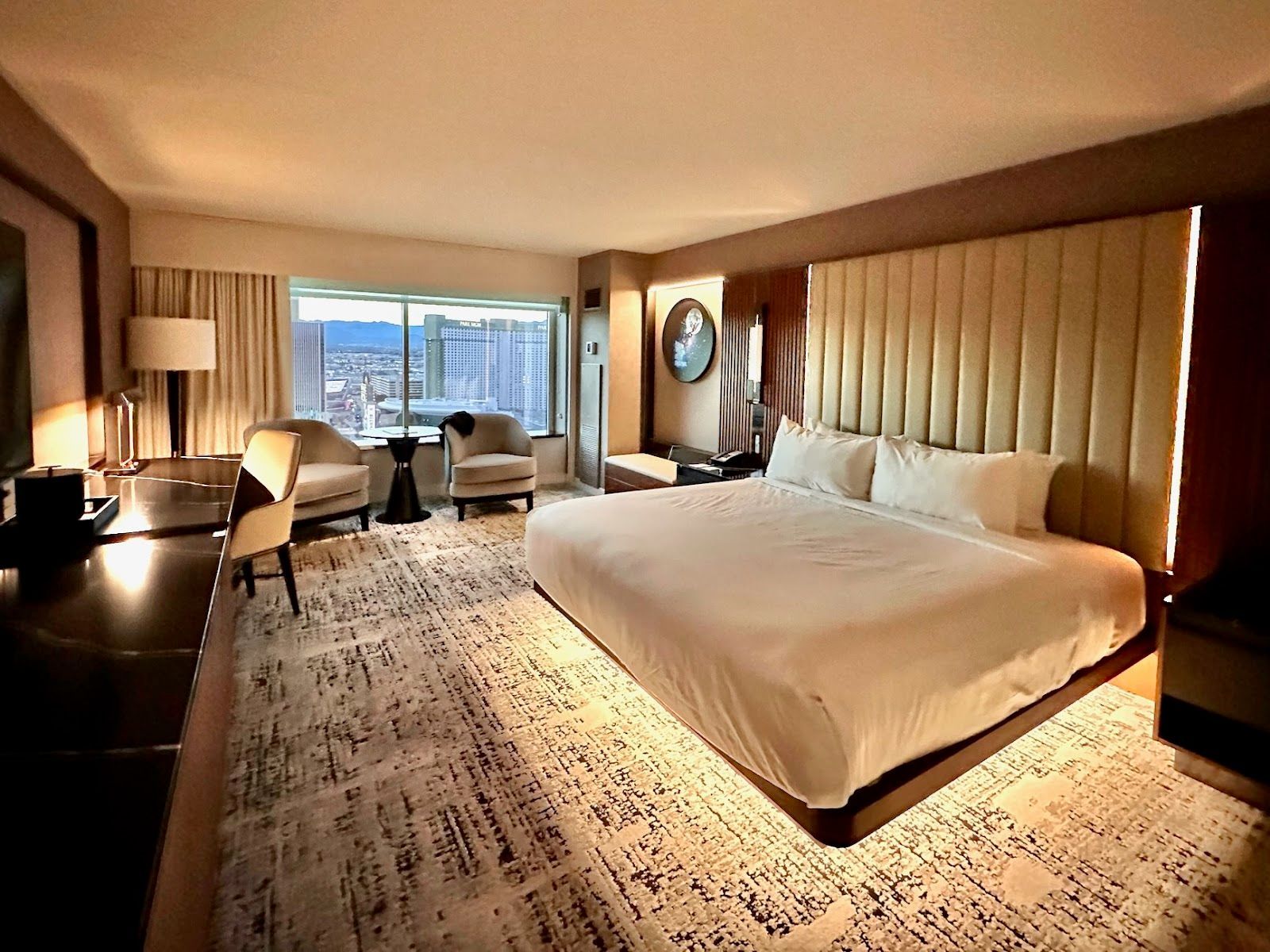 Long view of king room with work area settee chairs and view of Las Vegas skyline.