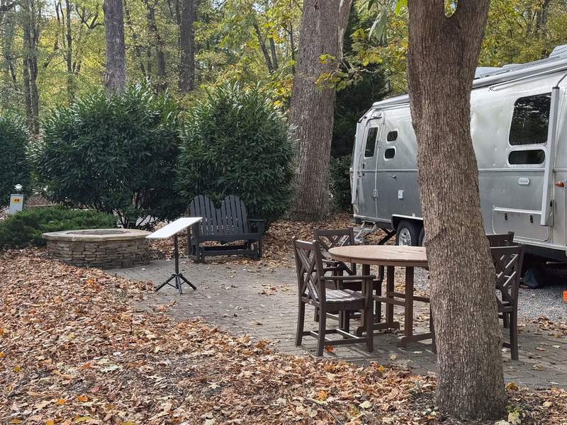 An Airstream camper on an RV site with outdoor patio and fire pit at the Townsend Great Smokies KOA