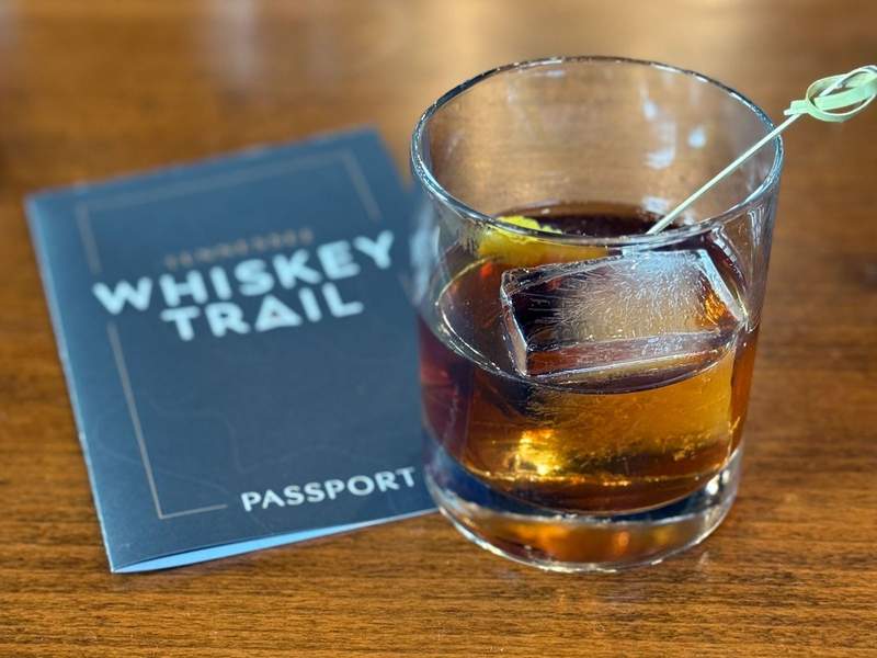 An Old Fashioned cocktail next to a Whiskey Trail passport.