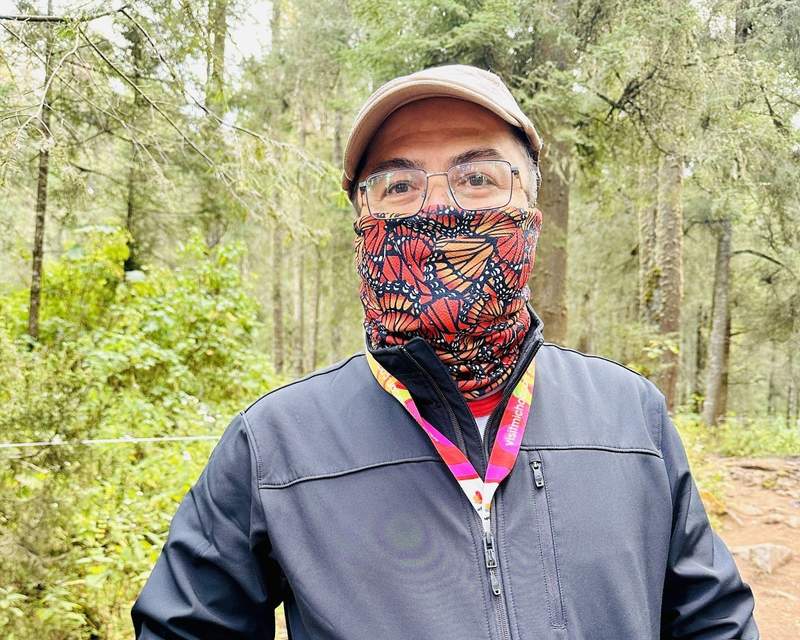 Male tour guide wearing a monarch neck gaiter in the reserve.