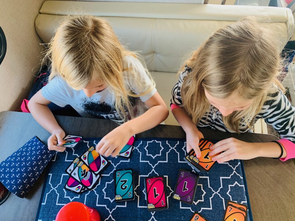Two young girls playing a board game on the kitchen table of an RVshare motorhome during a family vacation.