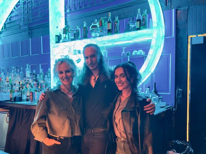 A mother and daughter pose with the distillery owner in front of the glowing blue bar at Obscure Distillery in Los Angeles. Photo credit: Kim Orlando